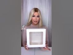 a woman is holding up a white box