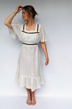 With a summery boho style, this 70s dress is an easy wear and has a really flattering cut. With the pretty lace and brown patterned ribbon to the empire waist and neckline and the tie around the waist to the back. The dress fastens with a zip to the back. Please note that the dress is a bit see through and you will need to wear natural underwear or a petticoat! Size: UK 10, Europe 38, US 6 Era: 1970s Brand: No label Material: polyester / cotton mix Care: Machine wash Condition: Good vintage with Brown Bohemian Dress With Square Neck, Brown Bohemian Square Neck Dress, Fitted Bohemian Midi Dress With Empire Waist, Summer Bohemian Lined Midi Dress, Beige Boho Dress With Lace Trim For Summer, Bohemian Fitted Midi Dress With Lace Trim, Fitted Bohemian Midi Dress With Lace Trim, Beige Bohemian Midi Dress With Lace Trim, Vintage Boho Dress For Summer Vacation