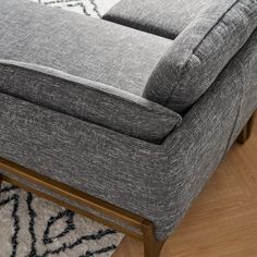 a gray couch sitting on top of a wooden floor next to a white and black rug