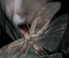 a close up of a person holding a bug in front of her face and mouth