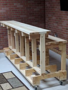 a bench made out of wooden planks sitting on top of a floor next to a brick wall