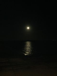 the moon is shining over the ocean at night