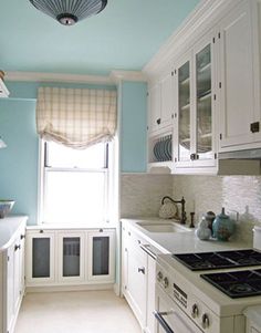 a kitchen with white cabinets and blue walls