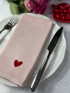 a white plate topped with a pink napkin and two red hearts on top of it