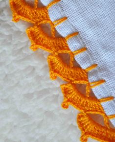 an orange crochet stitching on the side of a white cloth with yellow thread