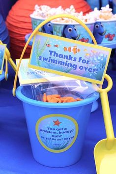 there are many buckets with food in them on the table at this birthday party