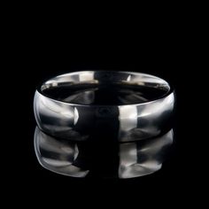 a close up view of a wedding ring on a black background, with the reflection of it