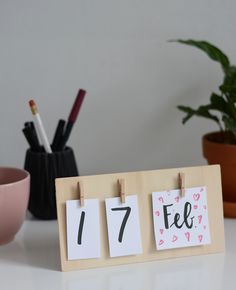 a wooden calendar with the number seven on it next to a cup and pen holder