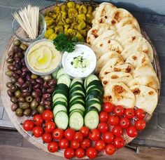 a platter filled with different types of vegetables and pita breads on top of each other