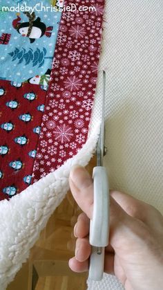 someone is cutting the edge of a quilt with scissors