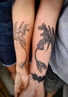 two people with tattoos on their arms holding each other's hands and one has a dragon tattoo on it