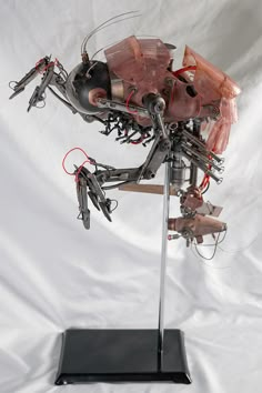 a metal sculpture with many wires attached to it's back legs and arms, on a black stand against a white background