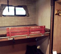 a red crate sitting on top of a wooden shelf in a room next to a window