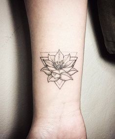 a lotus flower tattoo on the wrist is shown in black and grey ink, with geometric shapes