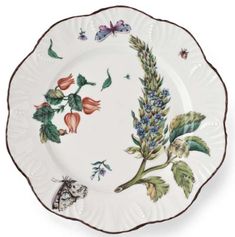 a white plate with flowers and butterflies on the rim, sitting against a white background