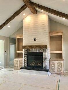 an empty living room with a fireplace and built in bookshelves