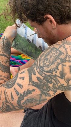 a man with tattoos on his arm sitting in a hammock