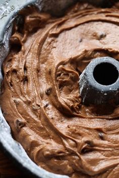 a cake pan filled with chocolate frosting on top of a wooden table