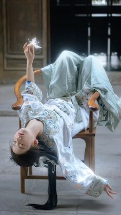 a woman laying on top of a wooden chair