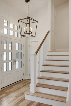 an entryway with stairs and chandelier next to the front door in a home