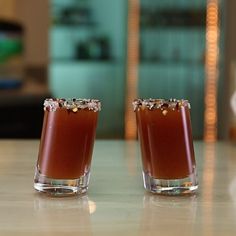 two shot glasses sitting on top of a table next to each other with sauce in them