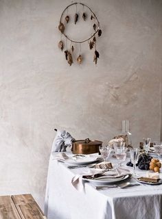 a table set for two with plates and silverware on it in front of a wall clock