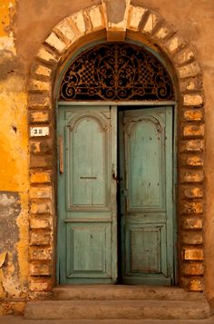 an old building with two blue doors and a stone arch over the entrance to it