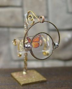 a small glass and metal object on a wooden table with a brick wall in the background