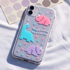 an iphone case with dinosaur stickers on it sitting next to a polka dot background