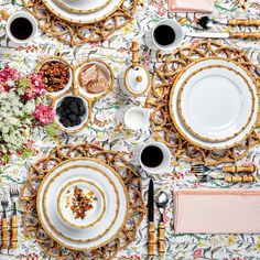 the table is set with plates, silverware and flowers