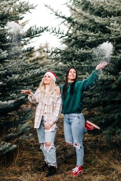 two women standing in front of trees throwing confetti into the air with their hands