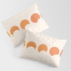 two pillows with orange circles on them sitting side by side in front of a white background