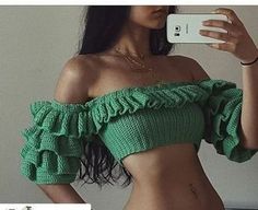 a woman taking a selfie with her cell phone while wearing a green crop top