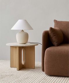 a lamp sitting on top of a wooden table next to a brown couch in a living room