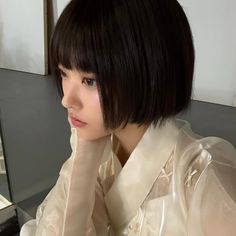 a woman with black hair wearing a white shirt and posing for a photo in front of a mirror