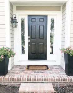 a front door with two planters on the steps and a welcome mat in front