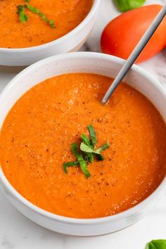 two white bowls filled with tomato soup and garnished with parsley