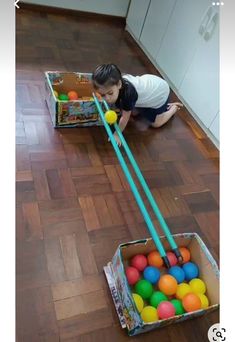 a child playing with balls in a box on the floor