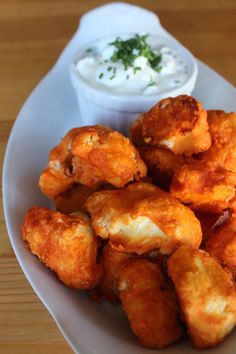 a white plate topped with tater tots next to a bowl of ranch dressing