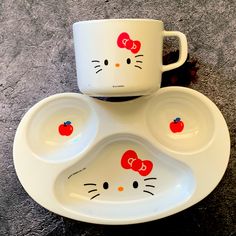 two hello kitty dishes with red bows on them and one has an apple in the middle