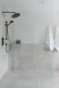 a white tiled bathroom with two shower heads