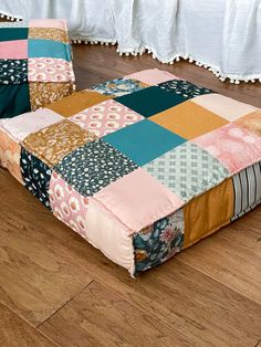 a multicolored patchwork bed sitting on top of a hard wood floor