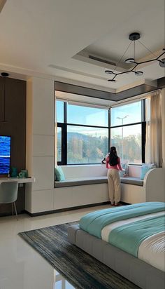 a woman sitting on a bed in front of a window looking out at the ocean