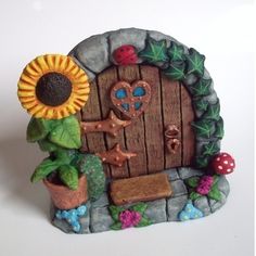 a small statue of a door with a sunflower and other items around it on a white surface