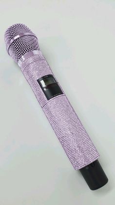 a purple microphone on a white surface with a black handle and the top part covered in sequins