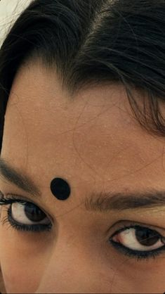 a close up of a woman's face with black circles on her forehead and eyebrows