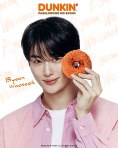 a man holding a donut up to his face with the words dunkin on it