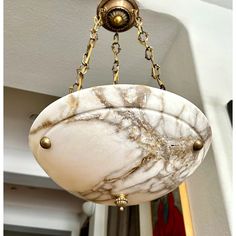 a light fixture hanging from the ceiling in a room with white walls and gold trim