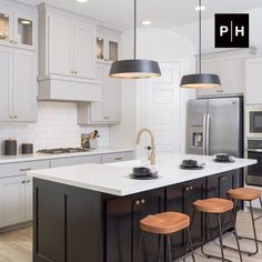 a kitchen island with stools and lights hanging from it's ceiling over the sink