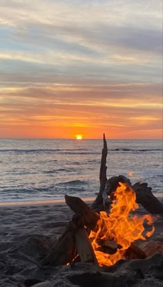 a campfire on the beach at sunset